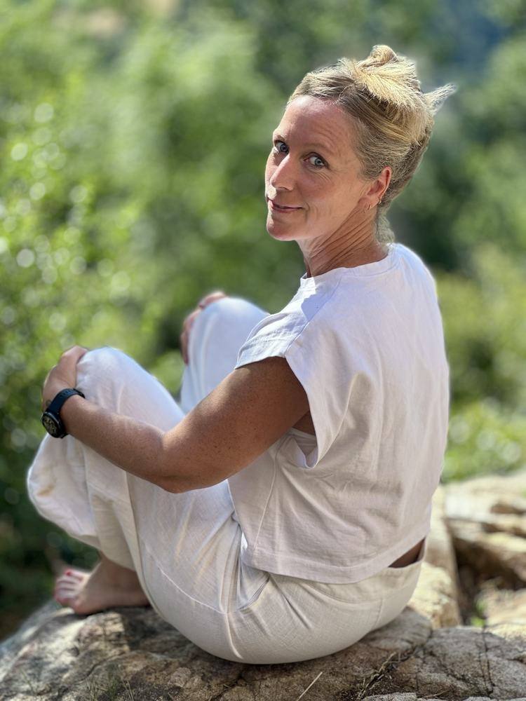 Chloé, naturopathe, assise sur un rocher en pleine nature