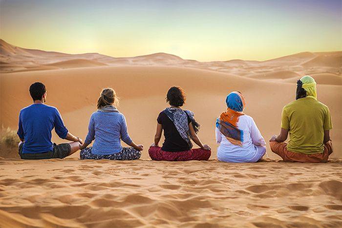 Groupe assis en méditation devant les dunes