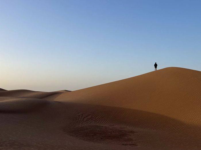 Silhouette d'un marcheur au sommet d'une grande dune