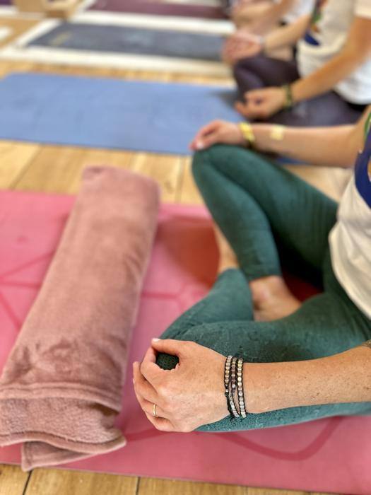 Cours de yoga : participants assis en tailleur sur leurs tapis