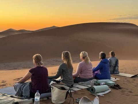 Méditation face aux dunes au coucher du soleil