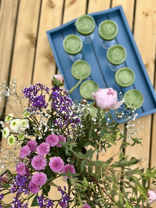 Plateau de jus verts et bouquet de fleurs sur la terrasse
