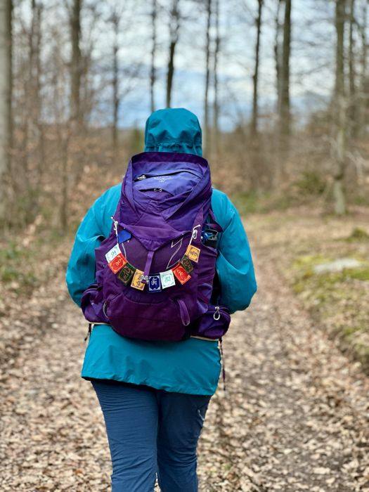 Randonneuse de dos, sac orné de drapeaux de prière, sur un chemin forestier