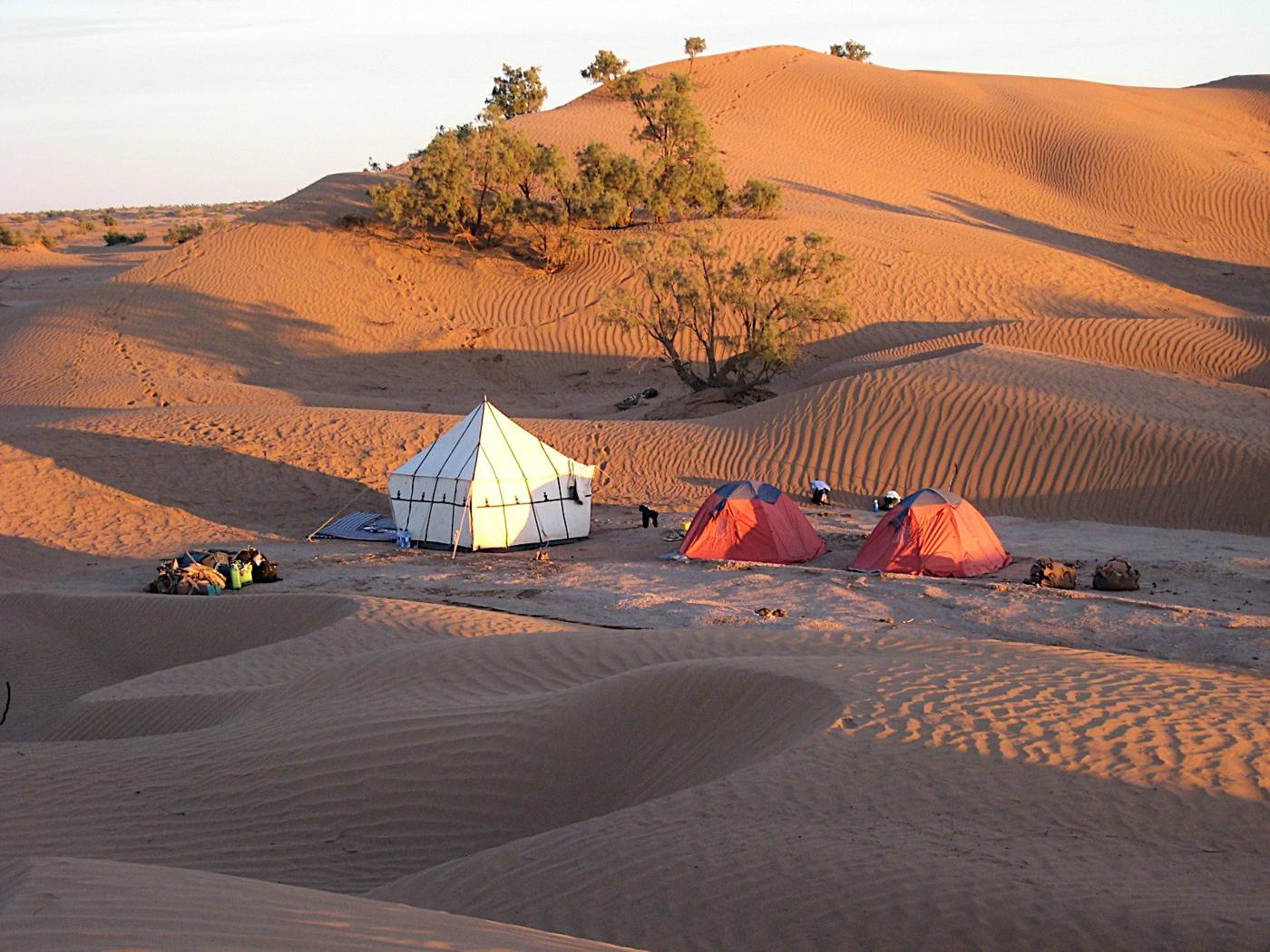 Campement de bivouac au creux des dunes, au coucher du soleil